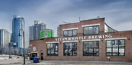 Edificio della Steam Whistle Brewing a Toronto con grattacieli sullo sfondo.