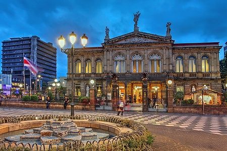 Teatro Nazionale del Costa Rica a San José illuminato di notte con persone nella piazza.