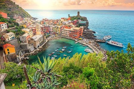 Vernazza all'alba con case colorate e mare blu nelle Cinque Terre, Italia.
