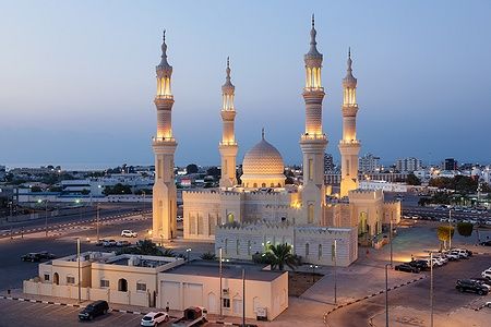 Zayed Mosque a Ras al-Khaimah illuminata al tramonto, con minareti imponenti.