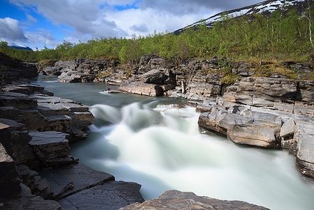 Fiume nel canyon di Abisko, Svezia, in lunga esposizione, con rocce e vegetazione.