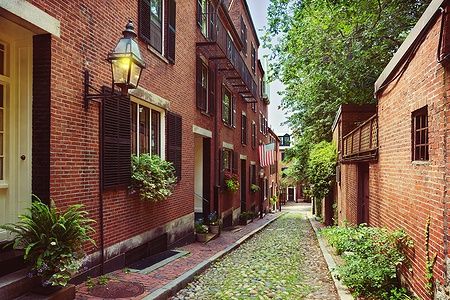 Strada acciottolata con edifici in mattoni e bandiera americana a Boston.