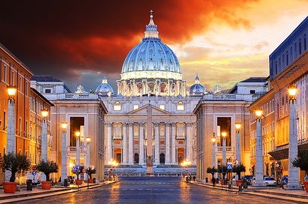 Vista della Basilica di San Pietro a Roma all'alba con un cielo dai colori caldi.