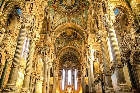 Interno della Basilica di Notre-Dame de Fourvière a Lione con decorazioni ricche e colonne imponenti.