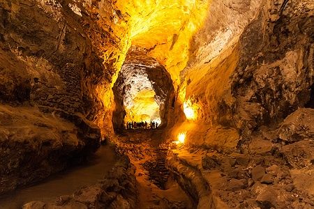 Interno illuminato della Cueva de los Verdes a Lanzarote con persone sullo sfondo.