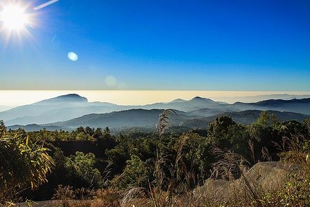 Panorama su Doi Inthanon con colline e cielo sereno sotto il sole.