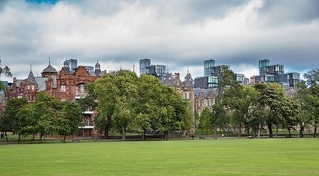 Prato verde e skyline moderna a Meadows park, Edimburgo, in una giornata nuvolosa.