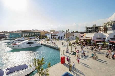 Limassol Marina a Cipro con yacht ormeggiati e una zona commerciale animata.