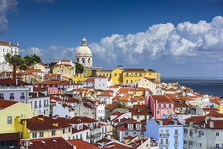 Skyline di Alfama a Lisbona con tetti colorati e cielo nuvoloso.