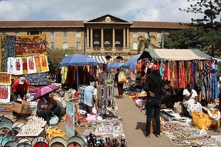 Masai Market a Nairobi con bancarelle di artigianato e Corte Suprema sullo sfondo.