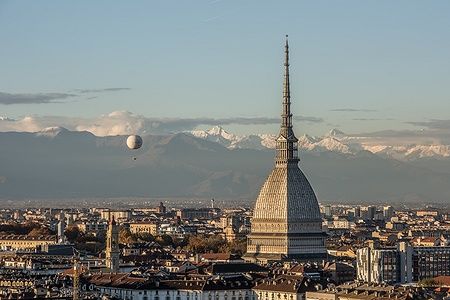 La Mole Antonelliana a Torino al tramonto con il panorama delle Alpi innevate.