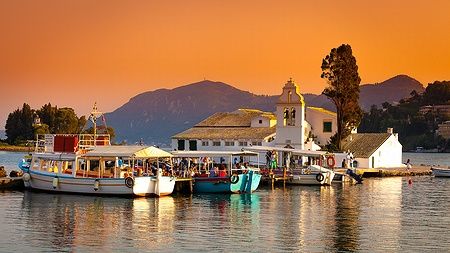 Monastero di Vlacherna a Corfù, Grecia, al tramonto con barche attraccate.