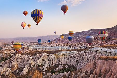 Mongolfiere colorate sorvolano il paesaggio roccioso della Cappadocia.