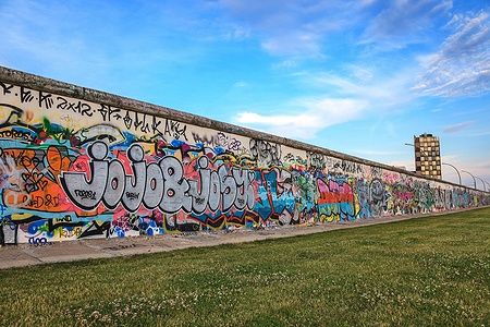 Il Muro di Berlino ricoperto di graffiti colorati sotto un cielo azzurro.