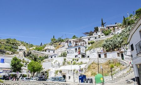 Quartiere Sacromonte a Granada con case-grotta e colline verdi.