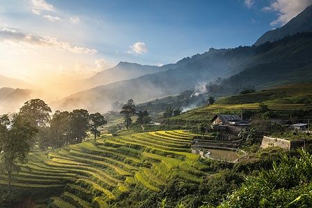 Campi di riso terrazzati al tramonto a Sapa, Vietnam, con montagne sullo sfondo.