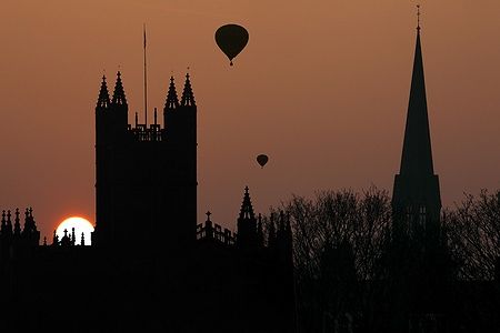 Bath Abbey all'alba con mongolfiere sopra il cielo arancione di Bath, Inghilterra.