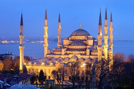La Moschea Blu di Istanbul illuminata al crepuscolo con sei minareti e il mare di Marmara sullo sfondo.