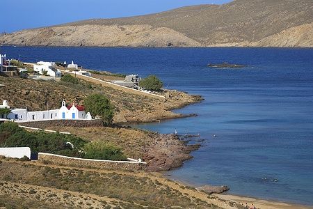 Vista della baia di Panormos a Mykonos con case bianche e mare blu.