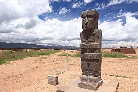 Statua di pietra nelle rovine di Tiwanaku, Bolivia sotto un cielo nuvoloso.