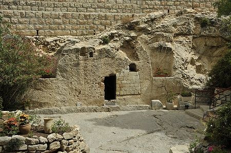 Tomba di Gesù Cristo scavata nella pietra a Gerusalemme, circondata da piante.