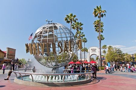 Il globo degli Universal Studios Hollywood con palme e persone intorno.