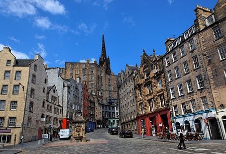 Edifici colorati di Victoria Street a Edimburgo sotto un cielo blu primaverile.