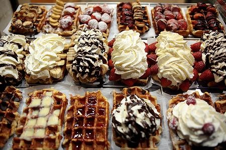 Waffle di Bruxelles con diverse guarnizioni colorate in esposizione.