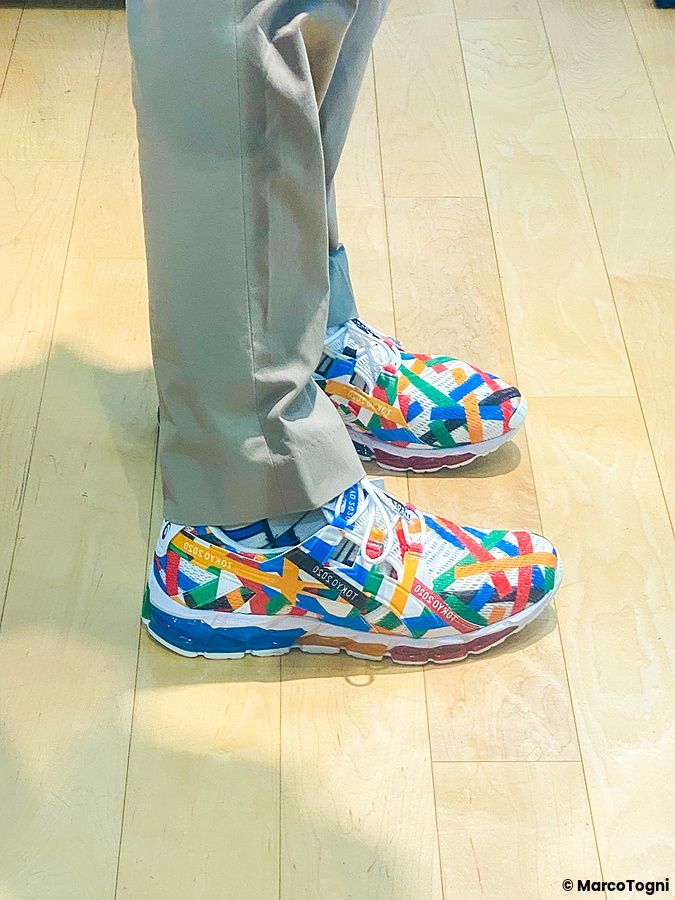Dettaglio di una persona che indossa le scarpe Asics per le Olimpadi di Tokyo 2020 con tomaia multicolore.