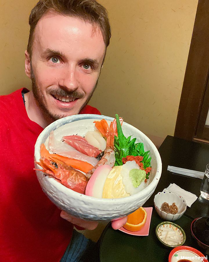 Marco Togni con ciotola di chirashi in un ristorante.
