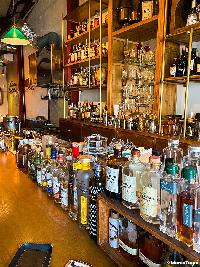 Vista ravvicinata del bancone del locale Cocktail Works a Karuizawa con una selezione di bottiglie di distillati.