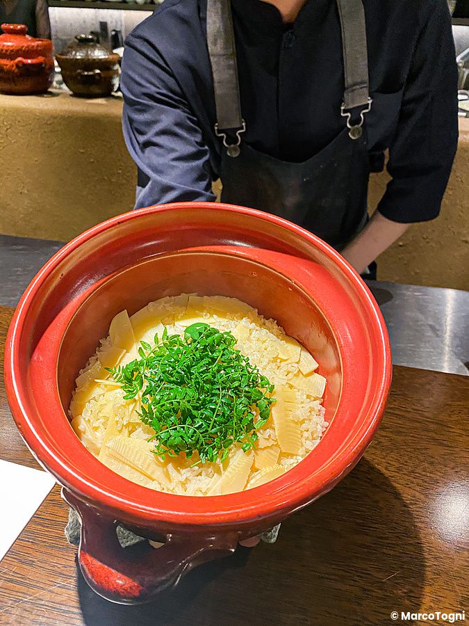Un piatto di riso con takenoko servito in una pentola di ceramica rossa presso il ristorante Denkushiflori a Tokyo.