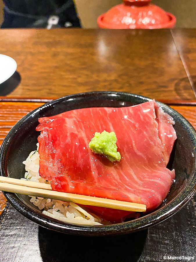 Un carpaccio di carne wagyu con wasabi sopra una ciotola di riso servito al ristorante Denkushiflori a Tokyo.