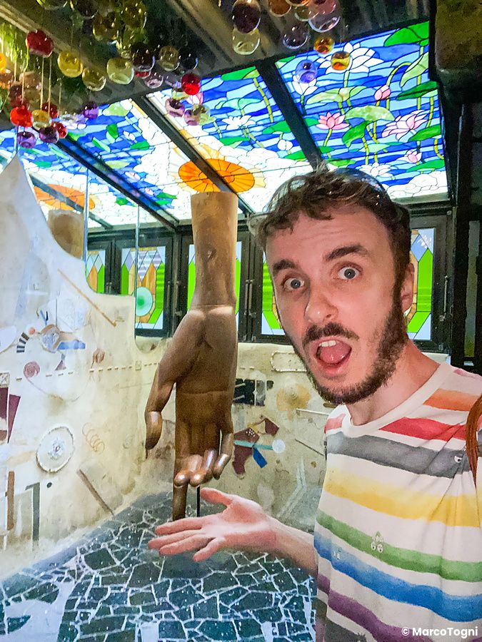 Marco Togni posa all'interno, al piano terra di El Dorado a Waseda, accanto a una scultura di mano in legno.