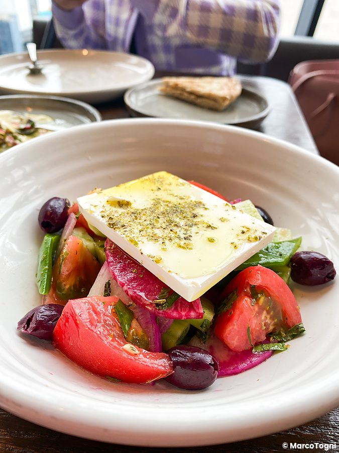Insalata greca con feta e pomodori servita in una ciotola bianca al ristorante The Apollo nel quartiere di Ginza.