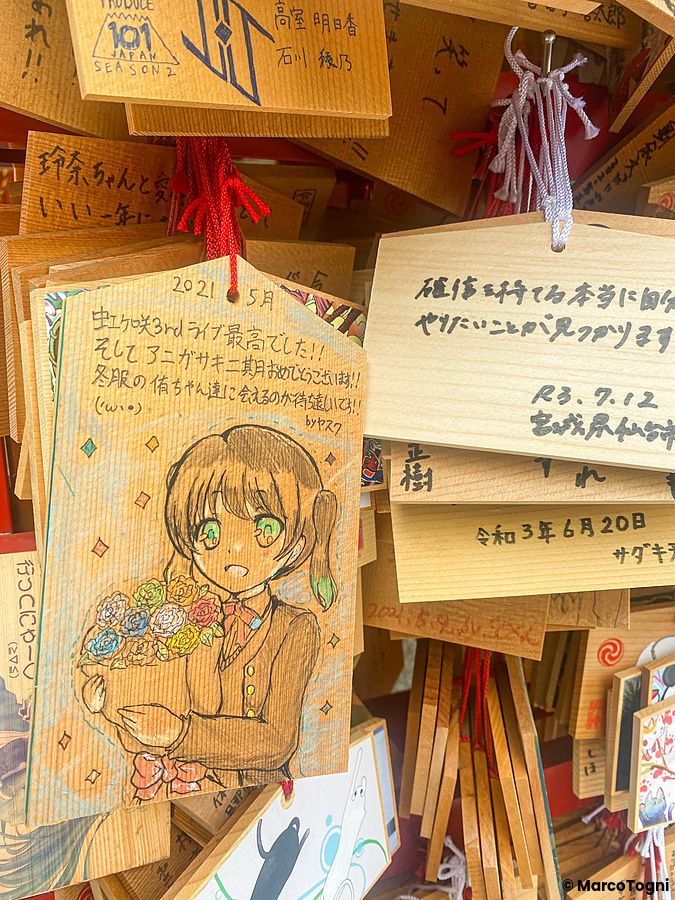 Tavolette votive in legno appese al santuario Kanda Myojin, con un disegno in stile manga in primo piano.