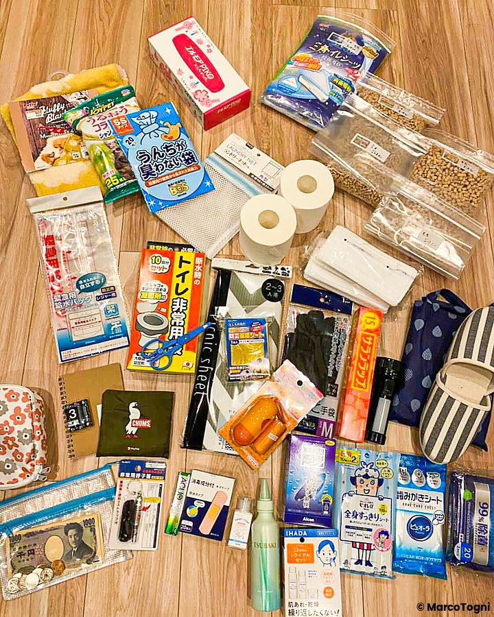 Kit di emergenza giapponese con vari articoli su un pavimento di legno.