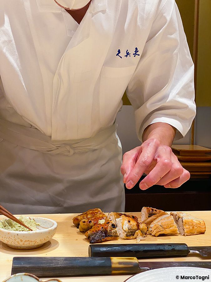 Un uomo, chef a Ginza Kyubey, prepara del sushi su un bancone di legno all'interno del ristorante a Tokyo.