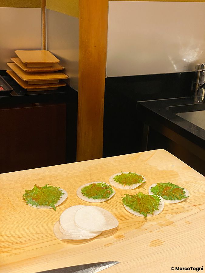 Snack con daikon e foglie di shiso preparato sul tagliere del ristorante Ginza Kyubey a Tokyo.