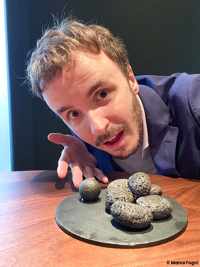 Marco Togni indica un piatto di sassi ricoperti di carbone vegetale, di cui solo uno contiene budin noir, al ristorante La...