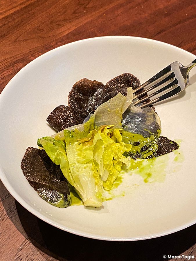 Tartufo, foglie di insalata grigliate, pesce spada e salsa di pesce serviti su un piatto bianco presso La Cime.
