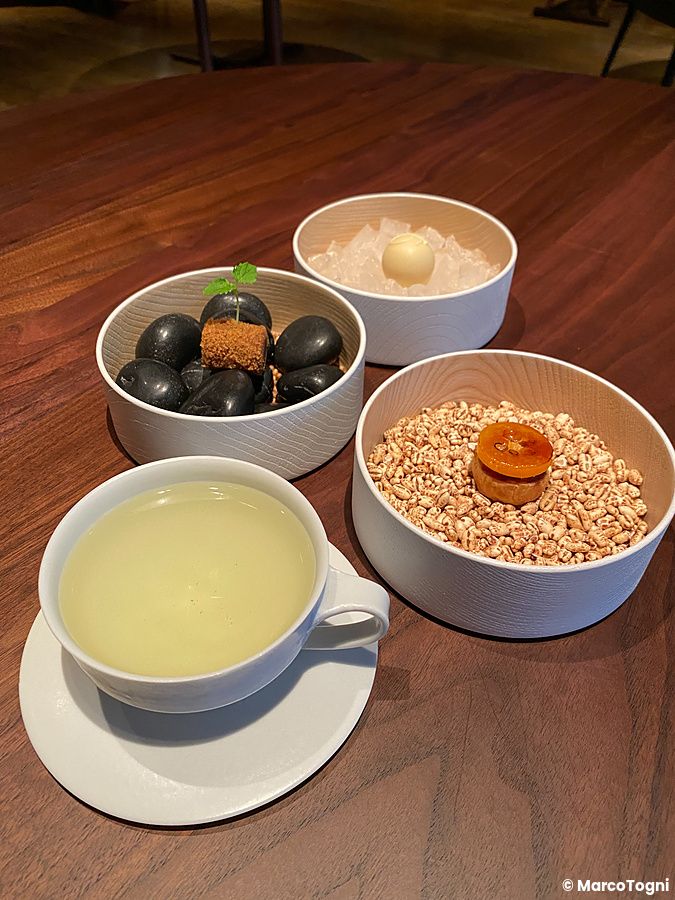 Tè di erbe fresche e piccola pasticceria serviti in eleganti ciotole di legno presso il ristorante La Cime a Osaka.