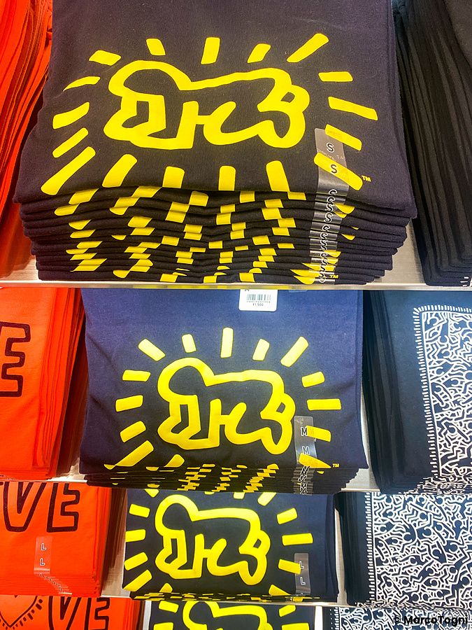 Magliette nere piegate con il disegno di un cane giallo di Keith Haring in esposizione su uno scaffale.