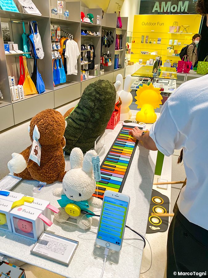 Interno del Moma Design Store a Tokyo con articoli in vendita tra cui peluche e una tastiera colorata su un bancone.