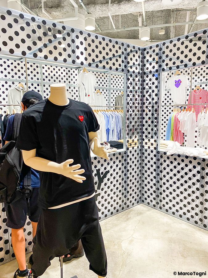 Interno del MoMA Design Store a Tokyo con pareti a pois bianchi e neri, manichino in primo piano e abbigliamento esposto.