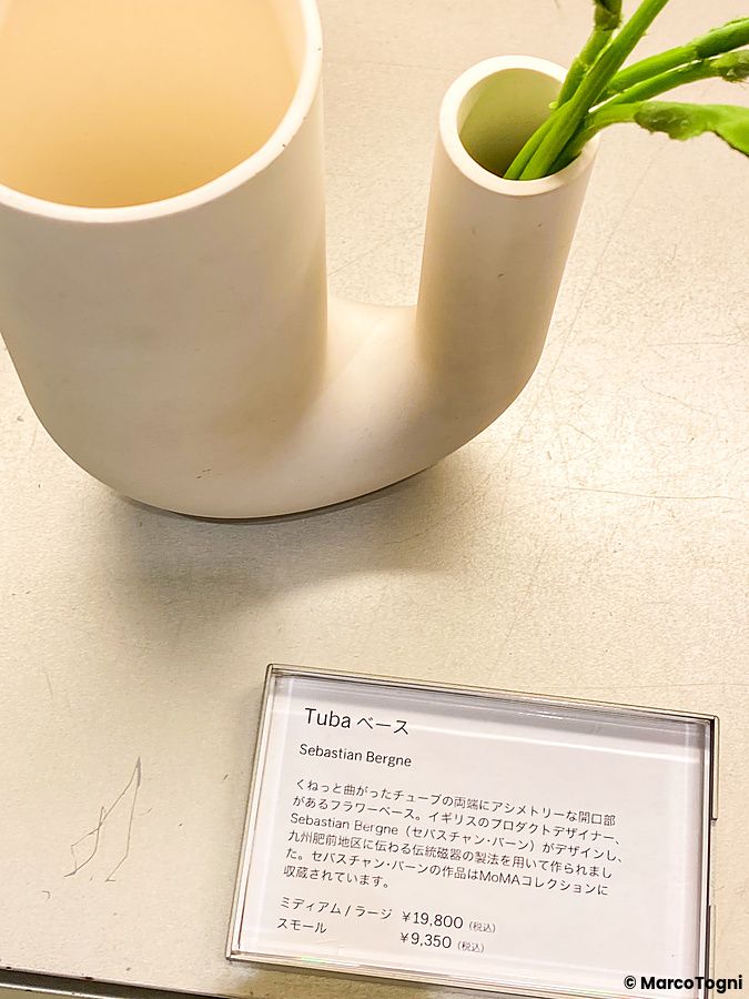 Vaso bianco dalle forme curve esposto su un ripiano con cartellino descrittivo al Moma Design Store di Tokyo.