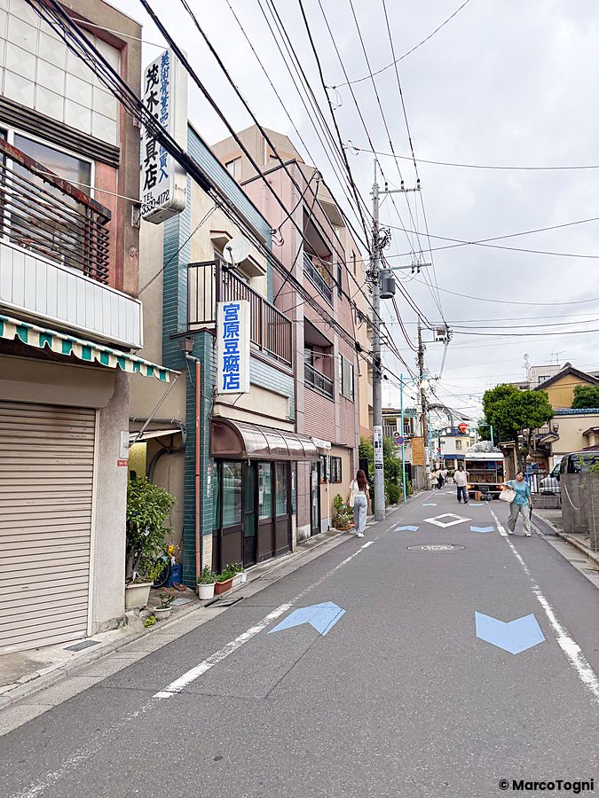 Veduta di una strada urbana con edifici e insegne dove si trova il ristorante a Ristorante Momose Shokudo a Tokyo.