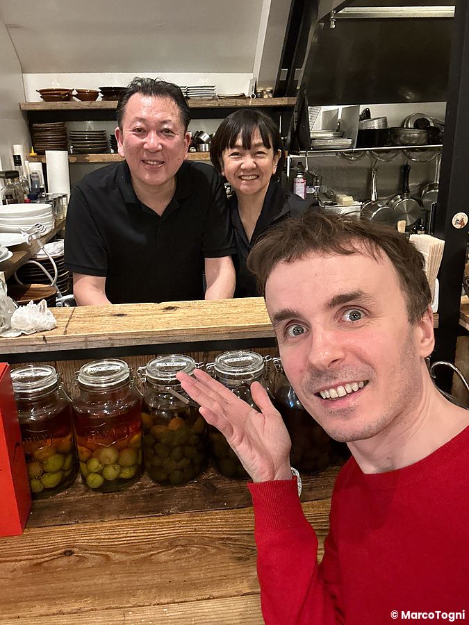 Selfie di Marco Togni con un uomo e una donna dietro il bancone del Ristorante Momose Shokudo con barattoli di vetro.