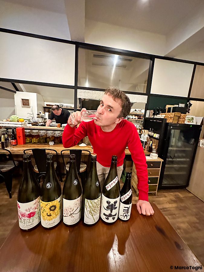 Marco Togni degusta sakè davanti a sei bottiglie allineate in una degustazione di sakè al Ristorante Momose Shokudo.
