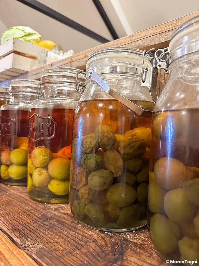 Barattoli di prugne ume in fermentazione su uno scaffale di legno.